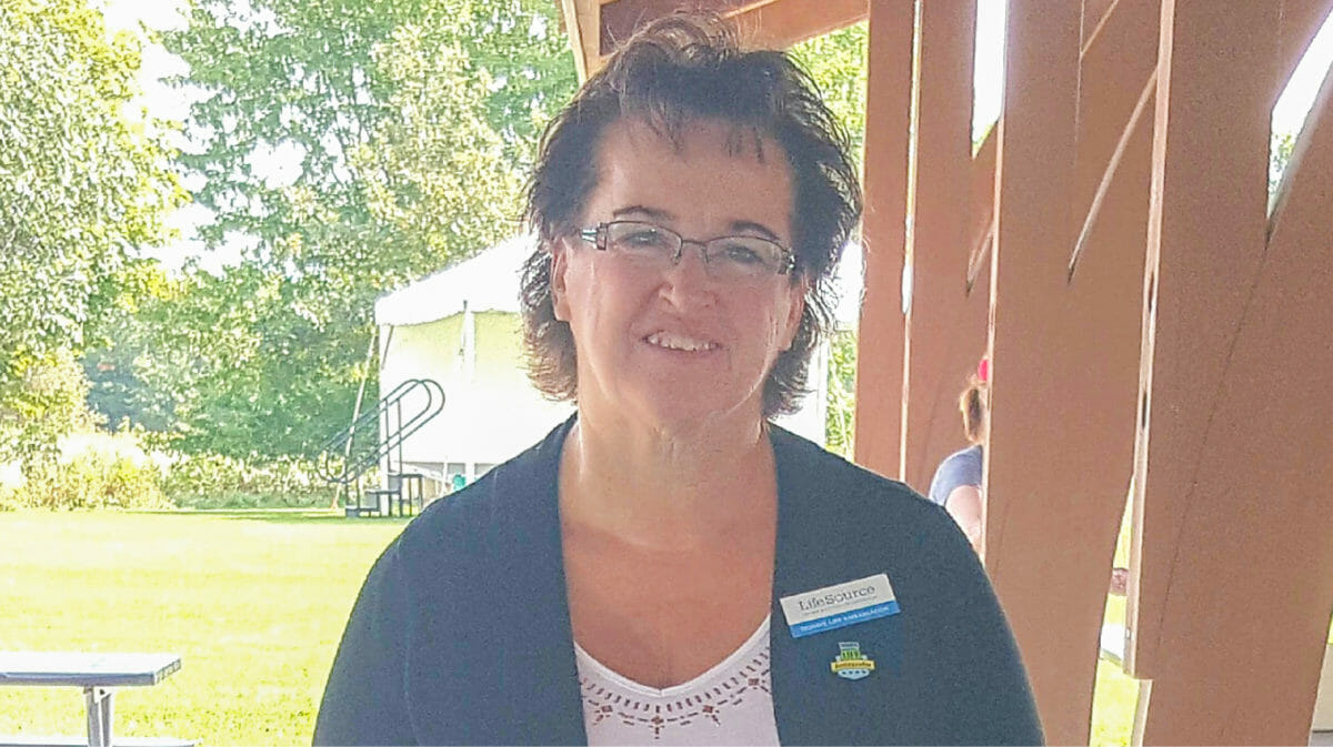 A woman wearing glasses and LifeSource pins on her shirt.