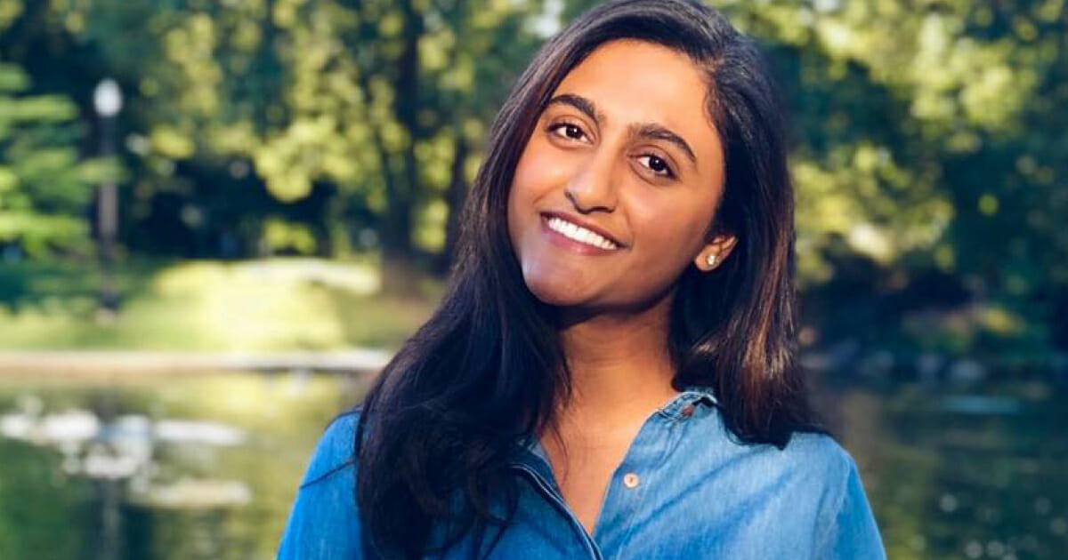 A woman wearing a blue denim shirt and smiling