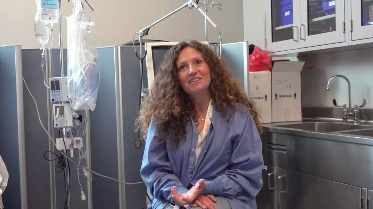 A woman wearing hospital scrubs in a hospital room