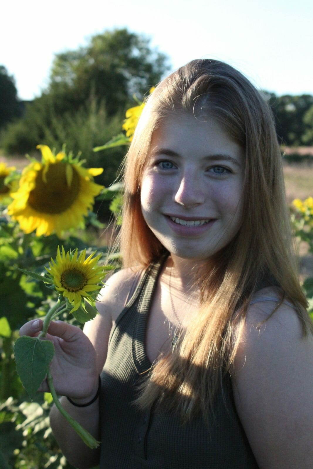 Miranda in sunflower field smiling at camera