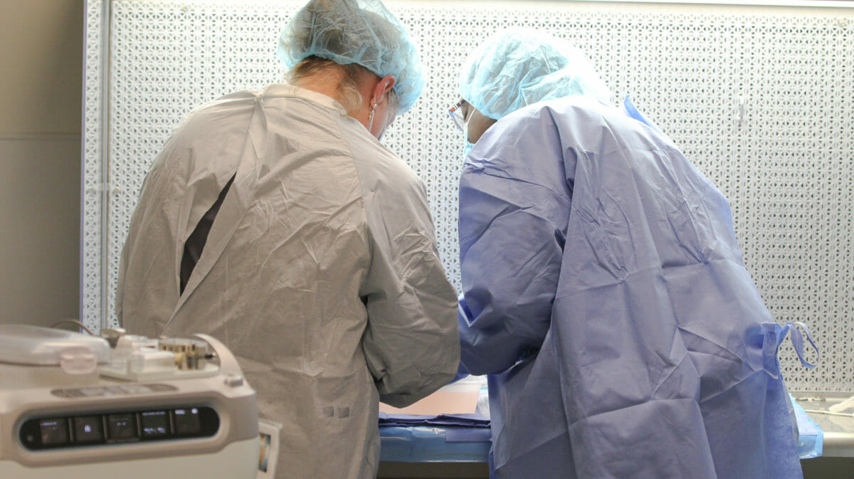 Two people in medical apparel, leaning over a table