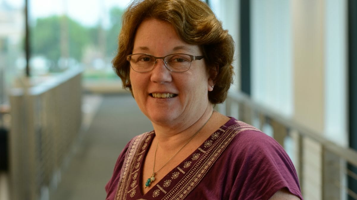 woman in maroon shirt smiling at camera