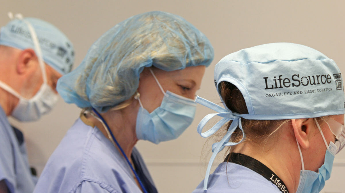 women in surgical clothing looking over something on table