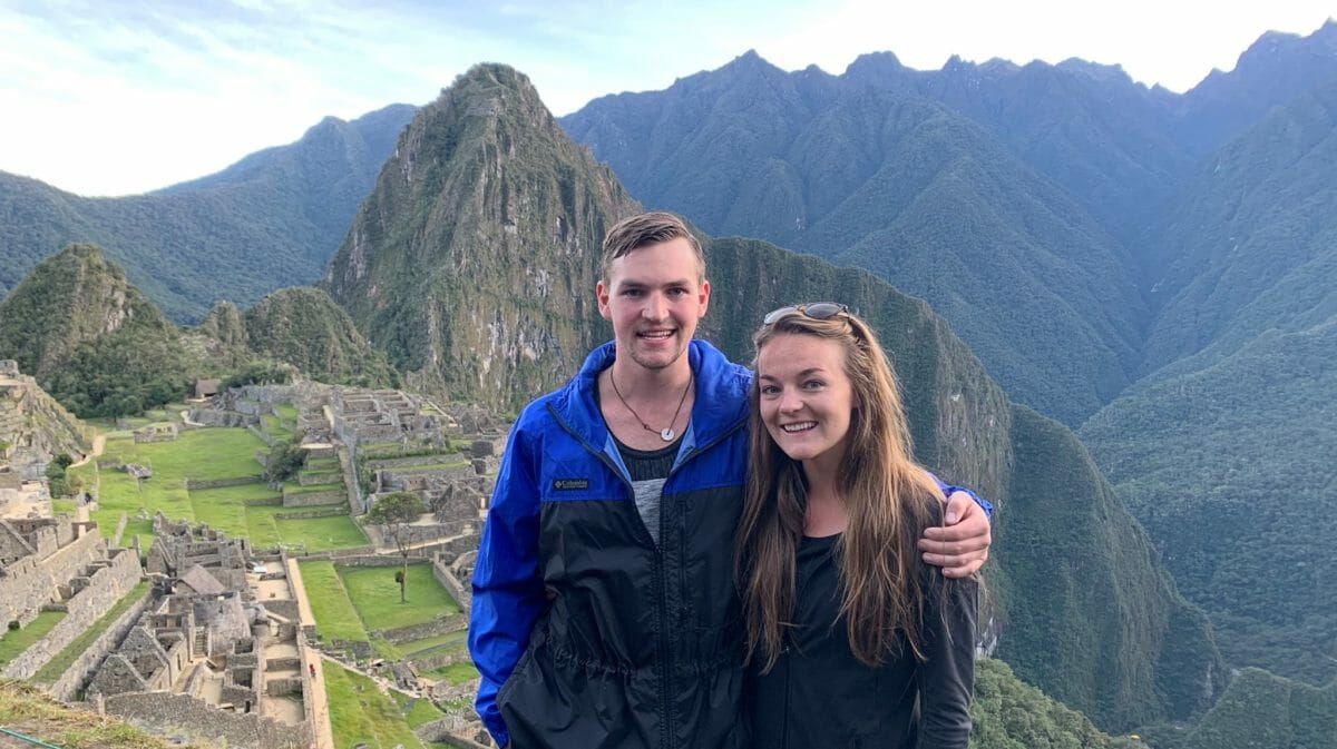 young man and woman smile at camera with beautiful, lush background