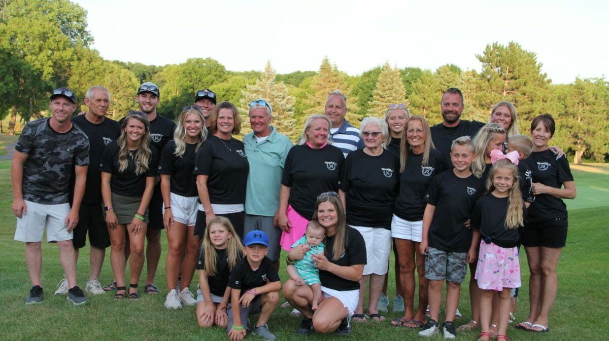 Family in matching shirts smile at camera at golf event