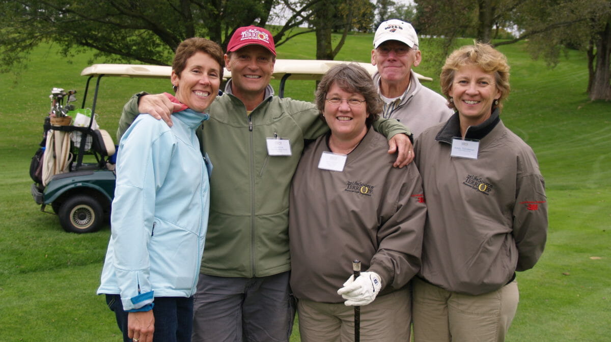 people in golf clothes smile at camera