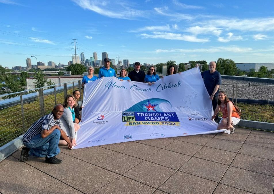 El equipo MN-DAK sostiene la bandera de la TGA en la sede de LifeSource