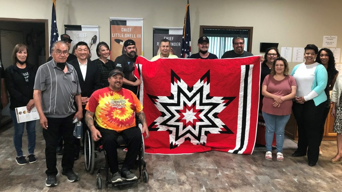 Group stand behind quilt and smile for photo