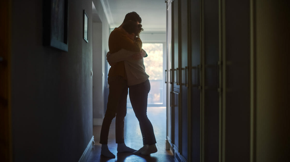 two people hug each other in a hallway.