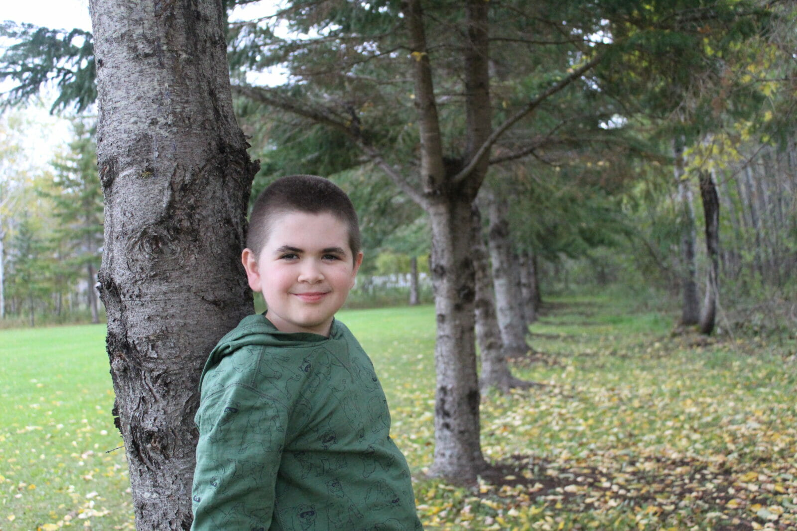 Jackson sonriente apoyado en un árbol.