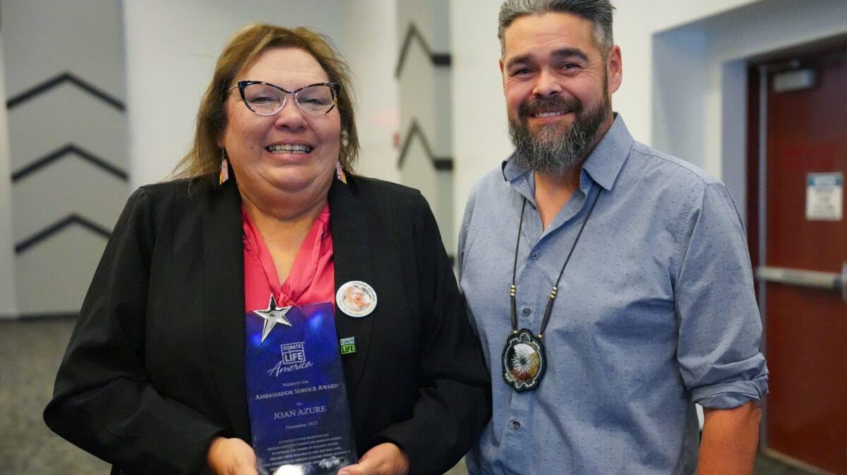 Joan Azure smiles while holding Donate Life America Award while standing next to Tribal Chairman, Jamie Azure.