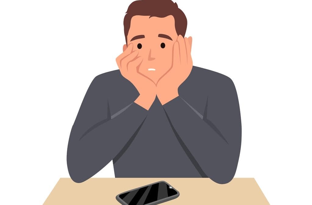 man sitting holding his face waiting anxiously for a call